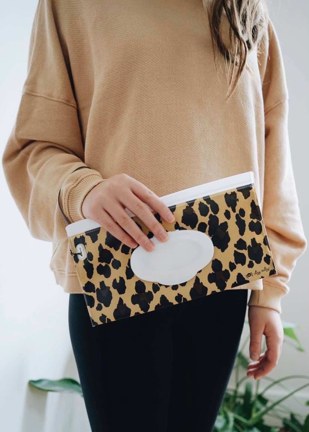 Person holding a leopard print Itzy Ritzy Take & Travel™ Pouch Reusable Wipes Case with silicone wristlet