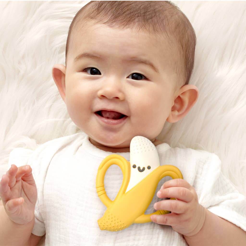 Baby holding Beckett the Banana Chew Crew Silicone Teether by Itzy Ritzy, providing soothing relief for teething with easy-to-grip handles.